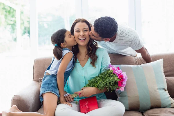 Mulher recebendo beijo de seu marido e filha na sala de estar — Fotografia de Stock
