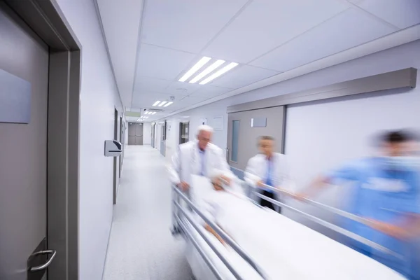 Лікарі і медсестра штовхають ліжко в коридор — стокове фото