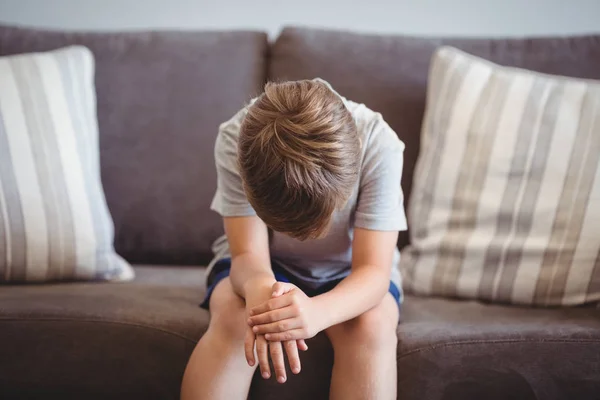 Niño molesto sentado en el sofá en el pasillo —  Fotos de Stock