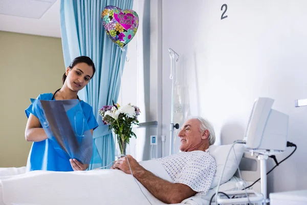 Medico femminile che discute il rapporto radiografico con il paziente anziano maschio nel reparto — Foto Stock