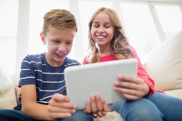 Geschwister nutzen digitales Tablet auf Sofa im Wohnzimmer — Stockfoto