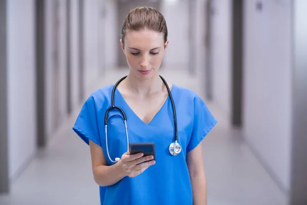 Dokter wanita menggunakan ponsel di koridor. — Stok Foto