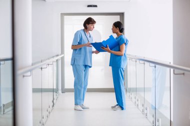 Nurse and doctor discussing over clipboard clipart