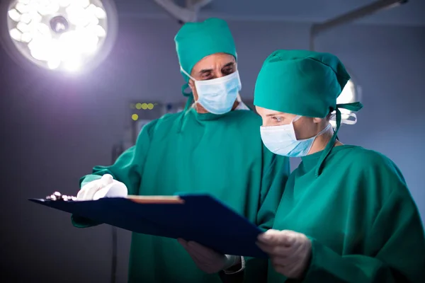 Cirujano masculino y femenino discutiendo sobre un informe médico del paciente — Foto de Stock