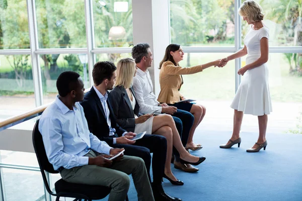 Female business executive shaking hands with a participant — Stock Photo, Image