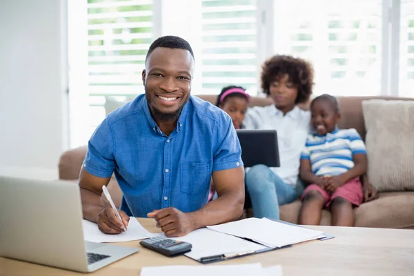 Hombre sonriente calculando facturas en casa — Foto de Stock