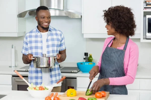 Couple souriant hachant des légumes dans la cuisine — Photo