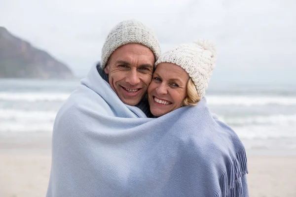 Äldre par insvept i filt på stranden — Stockfoto