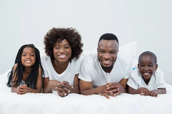 Porträt von Eltern und Kindern auf dem Bett liegend — Stockfoto