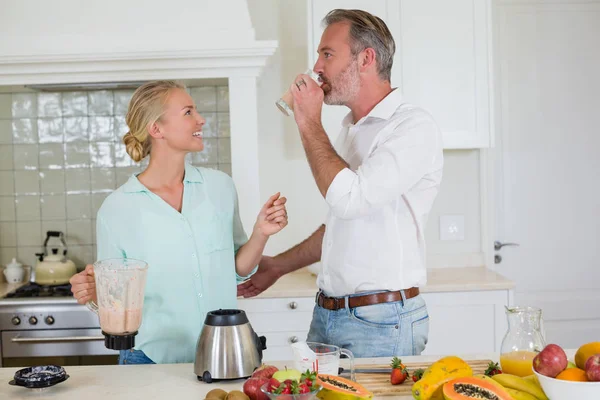 Sonriente pareja teniendo jugo en la cocina en casa —  Fotos de Stock