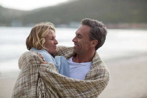 Ouder paar gewikkeld in een deken op het strand — Stockfoto