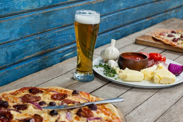 Pizza italiana servida con un vaso de cerveza sobre tabla de madera — Foto de Stock