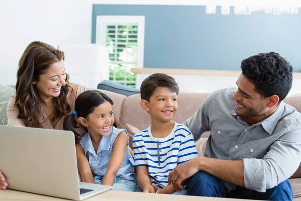 Родители и дети, использующие ноутбук в гостиной — стоковое фото