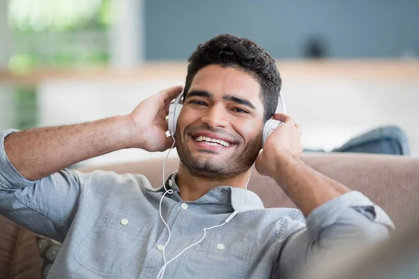 Człowiek, słuchanie muzyki na słuchawkach w salonie w domu — Zdjęcie stockowe