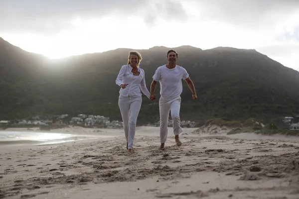 Dospělý pár, běžící na pláži — Stock fotografie