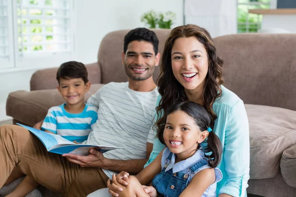 Portrait de parents et d'enfants assis sur un canapé et lisant un livre — Photo