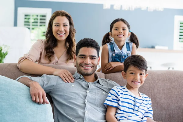 Porträtt av lyckliga föräldrar och barnen sitter på soffan i vardagsrummet — Stockfoto