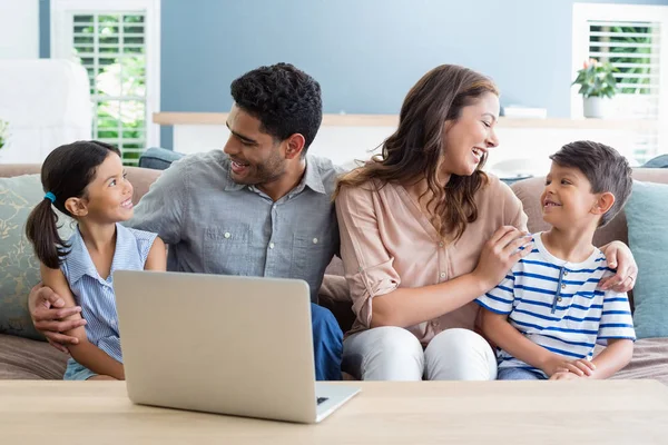 Lyckliga föräldrar och barnen sitter med arm runt i vardagsrummet — Stockfoto