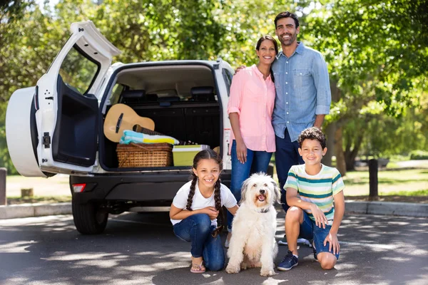 Porträt einer glücklichen Familie, die neben ihrem Auto Spaß hat — Stockfoto