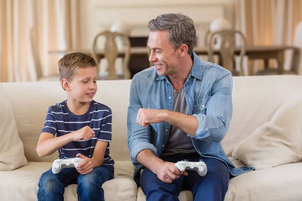 父亲和儿子给拳头撞到彼此在客厅里玩视频游戏时 — 图库照片