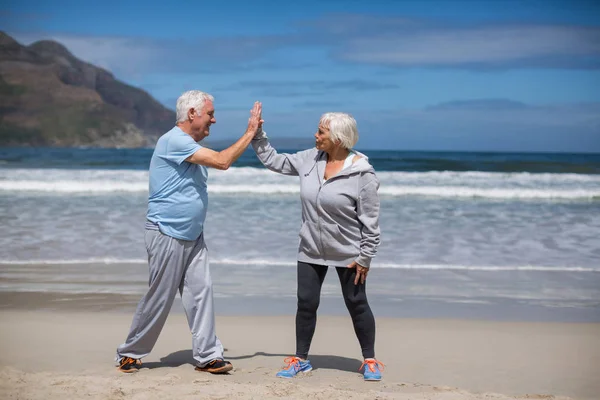 Pareja mayor dando choco cinco después del ejercicio en la playa —  Fotos de Stock