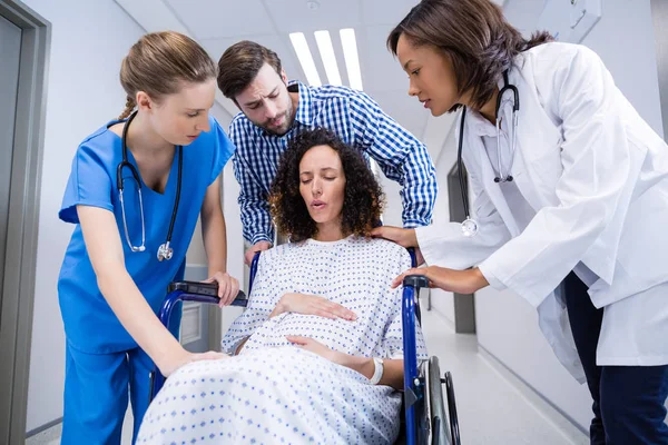 Medici e uomo confortante donna incinta in corridoio — Foto Stock