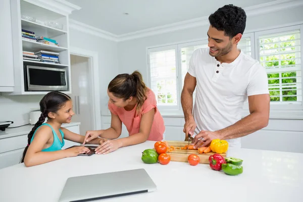 Madre e figlia utilizzando tablet digitale e padre che la guarda in cucina — Foto Stock