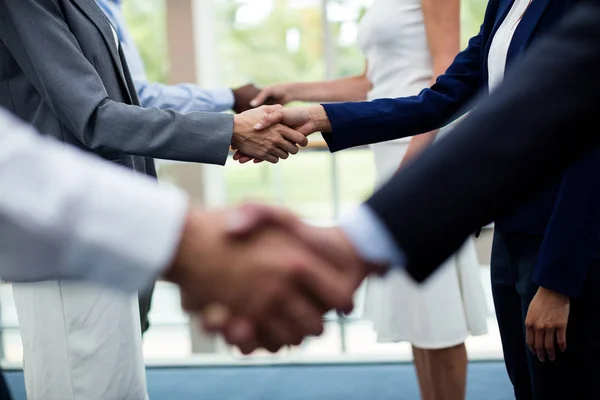 Seção intermediária de executivos de negócios apertando as mãos uns dos outros — Fotografia de Stock