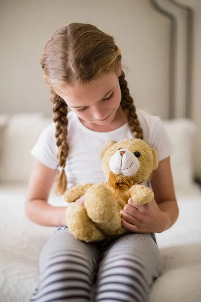 Dívka držící medvídek na lůžku v ložnici — Stock fotografie