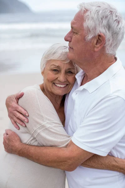 Senior paar omhelzen elkaar op het strand — Stockfoto