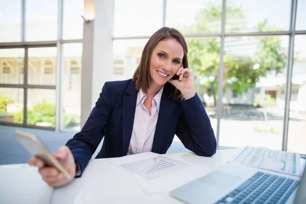 Affärskvinna sitter vid skrivbord och använda mobiltelefon — Stockfoto