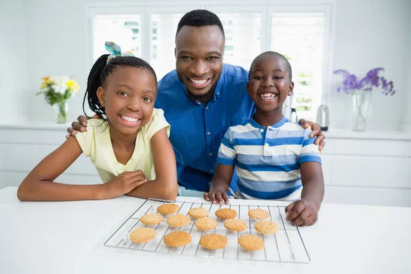 Portrait of father and kids with cookies on table