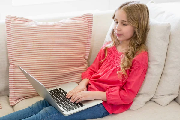 Menina usando laptop no sofá na sala de estar — Fotografia de Stock
