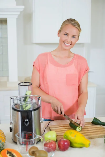 Gülümseyen kadın bir salatalık doğrama kurulu üzerinde kesme — Stok fotoğraf