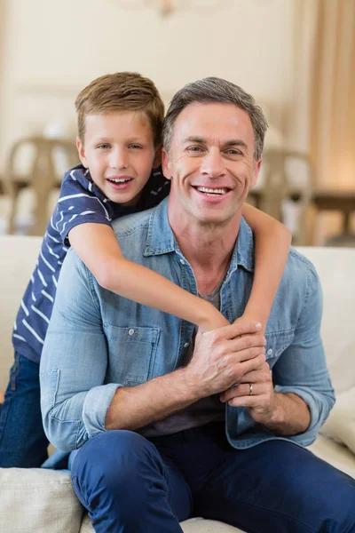 Usmívající se syn všeobjímající otce v obývacím pokoji — Stock fotografie