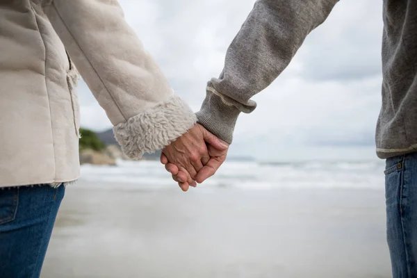 Pareja de pie con las manos en la playa — Foto de Stock