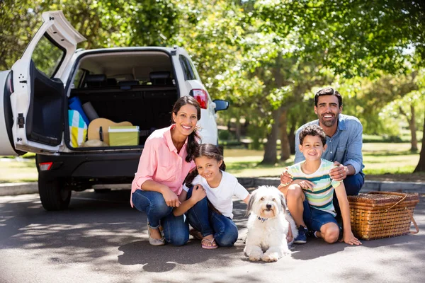 Lycklig familj på picknick sitter bredvid sin bil — Stockfoto