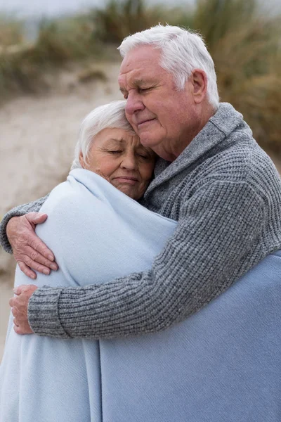 Äldre par insvept i sjal på stranden — Stockfoto