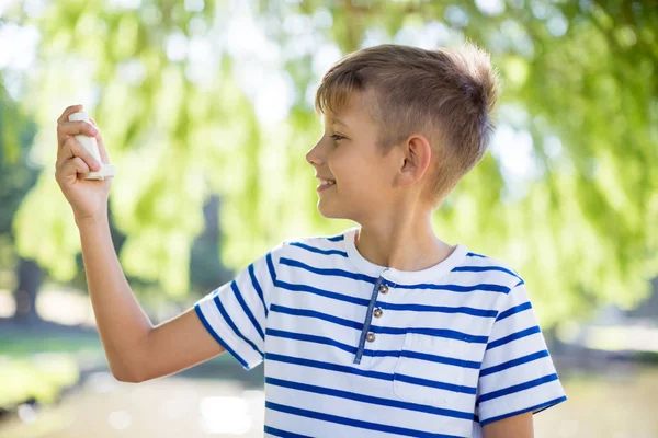 Pojken håller astmainhalator i park — Stockfoto