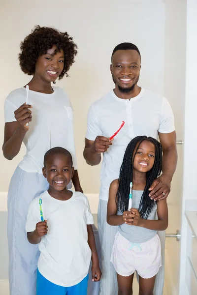 Genitori e bambini in piedi con spazzolino da denti in bagno a casa — Foto Stock
