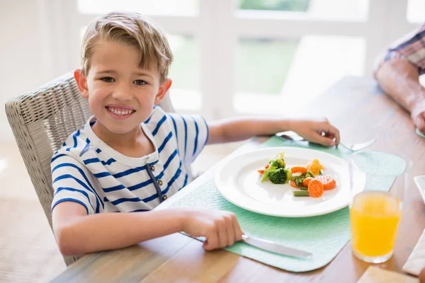 Roztomilý chlapec s jídlem na jídelní stůl — Stock fotografie