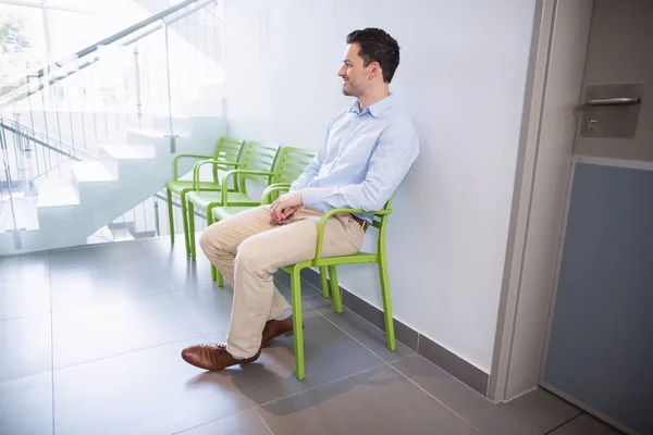 Uomo seduto sulla sedia nel corridoio dell'ospedale — Foto Stock