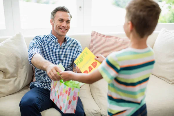 Padre recibiendo un regalo de su hijo en la sala de estar —  Fotos de Stock