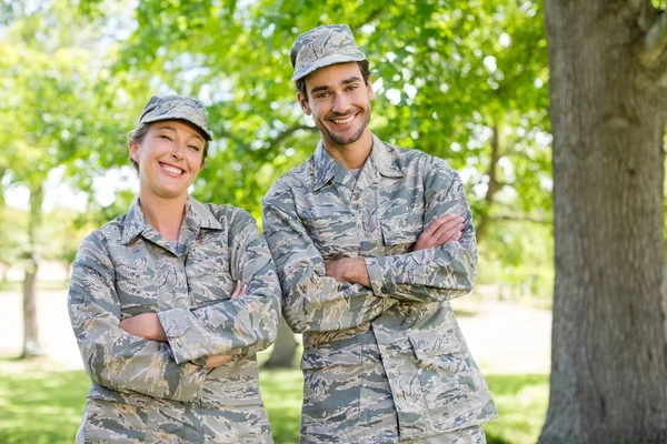 Portrait of a military couple standing with arms crossed in park