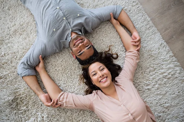 Porträtt av lyckliga par liggande på matta i vardagsrummet — Stockfoto