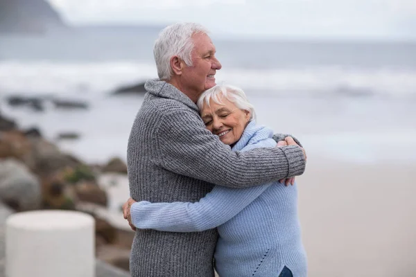 Старшая пара обнимает друг друга на пляже — стоковое фото