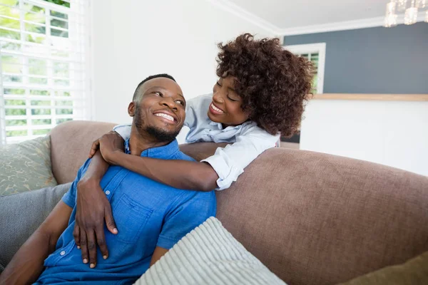 Casal feliz abraçando no sofá na sala de estar em casa — Fotografia de Stock