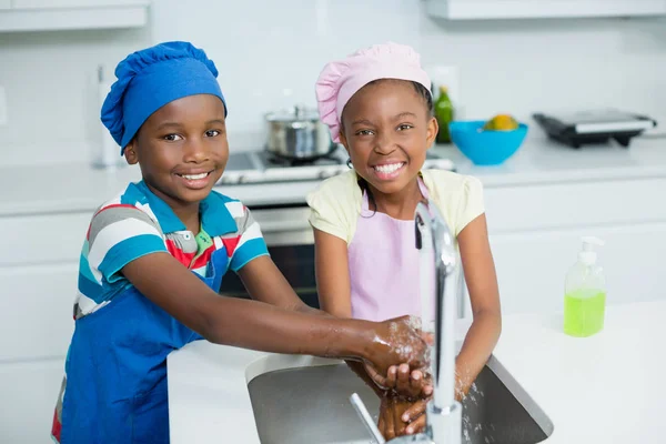 Братья и сёстры моют руки на кухне дома — стоковое фото