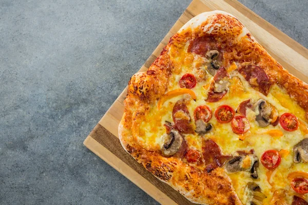 Pizza servida en una tabla de cortar sobre una tabla de madera — Foto de Stock