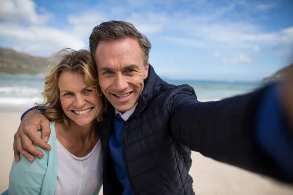 Pareja madura sonriendo a la cámara en la playa —  Fotos de Stock